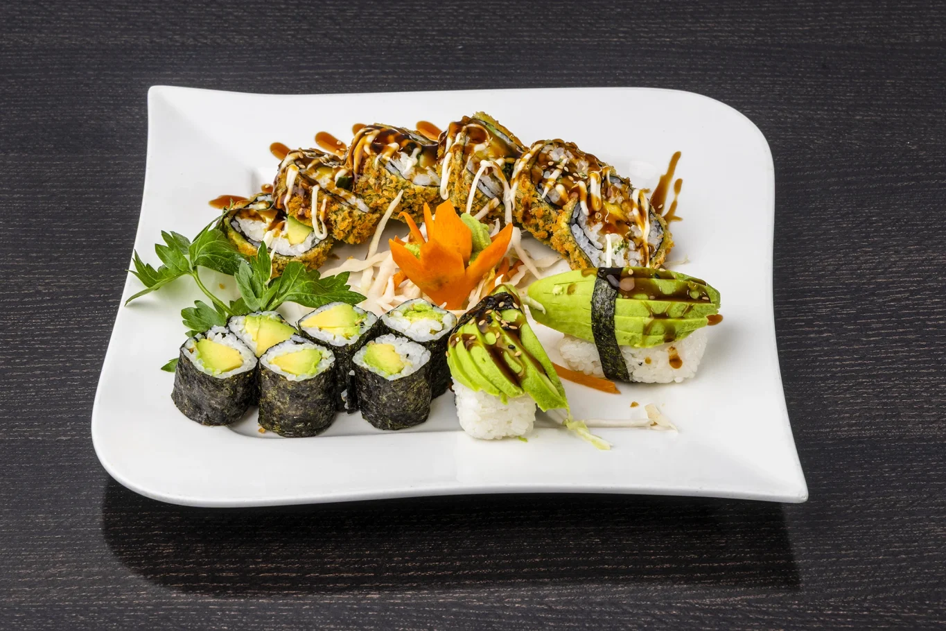 Ein Teller mit verschiedenen Sushi-Rollen, eingelegtem Gemüse und einer Garnitur aus Karotten.