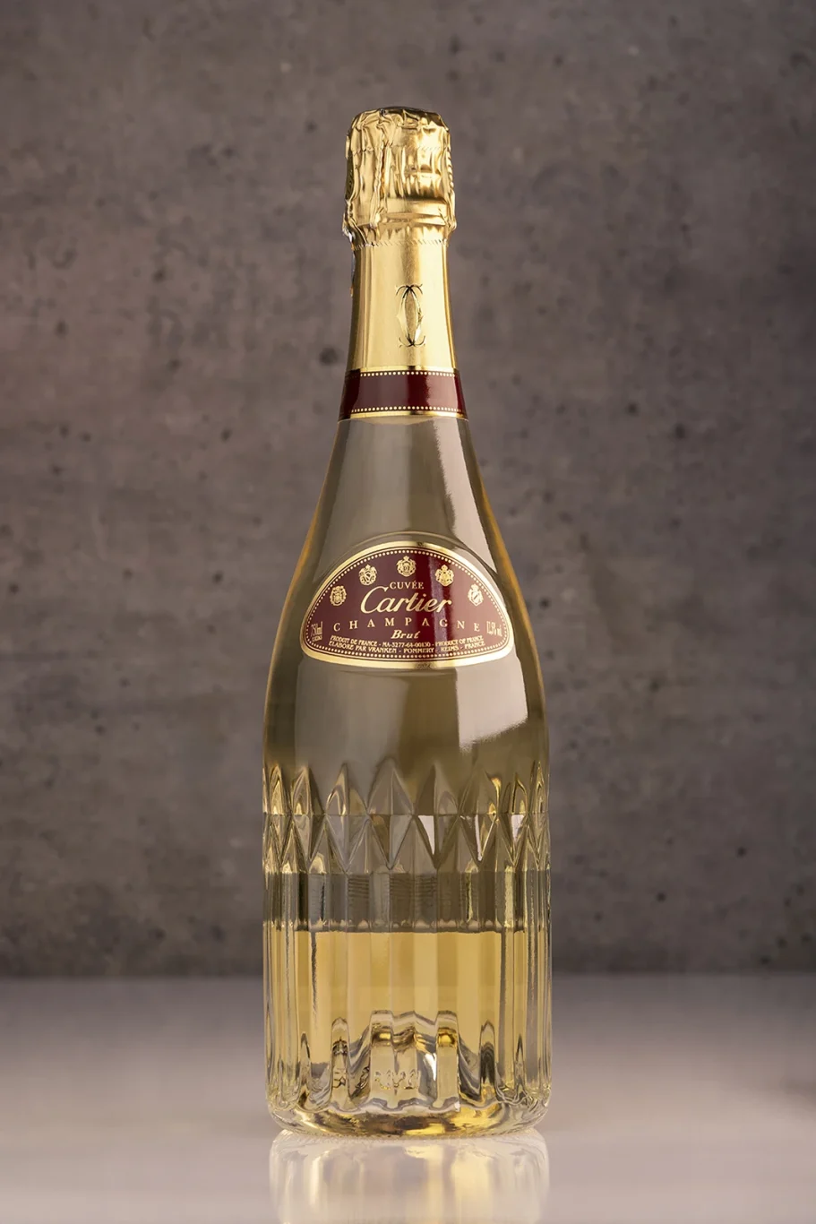 Eine Flasche Champagner mit goldfarbener Etikette vor einem grauen Hintergrund.