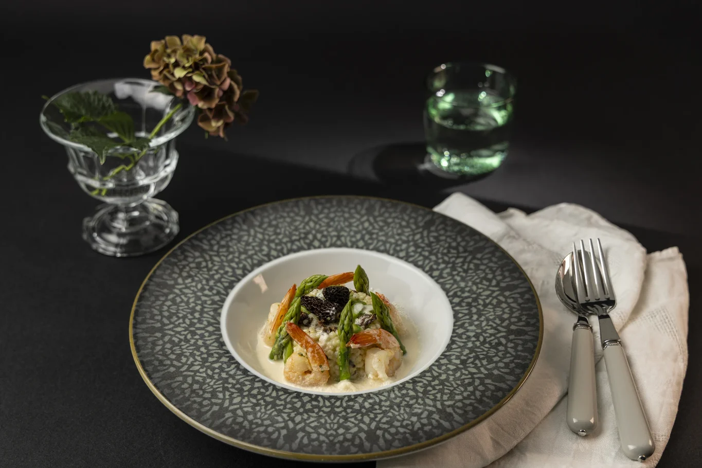 Risotto mit grünem Spargel, Morcheln und Shrimps auf dekorativem Teller.