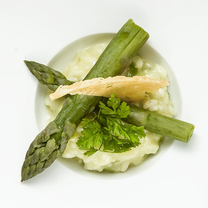 Spargelrisotto auf weißem Teller.
