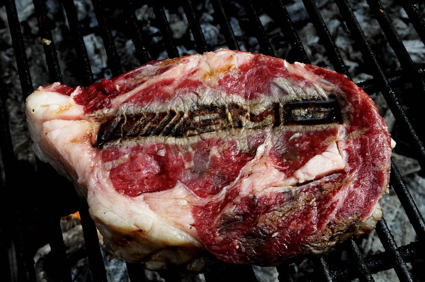 Saftiges Steak auf einem Grill mit sichtbarer Grillmarkierung.