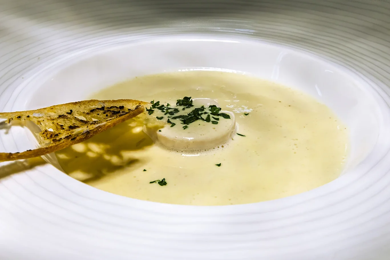 Cremige Suppe mit einem Scheibe Gemüse und gehackten Kräutern garniert.